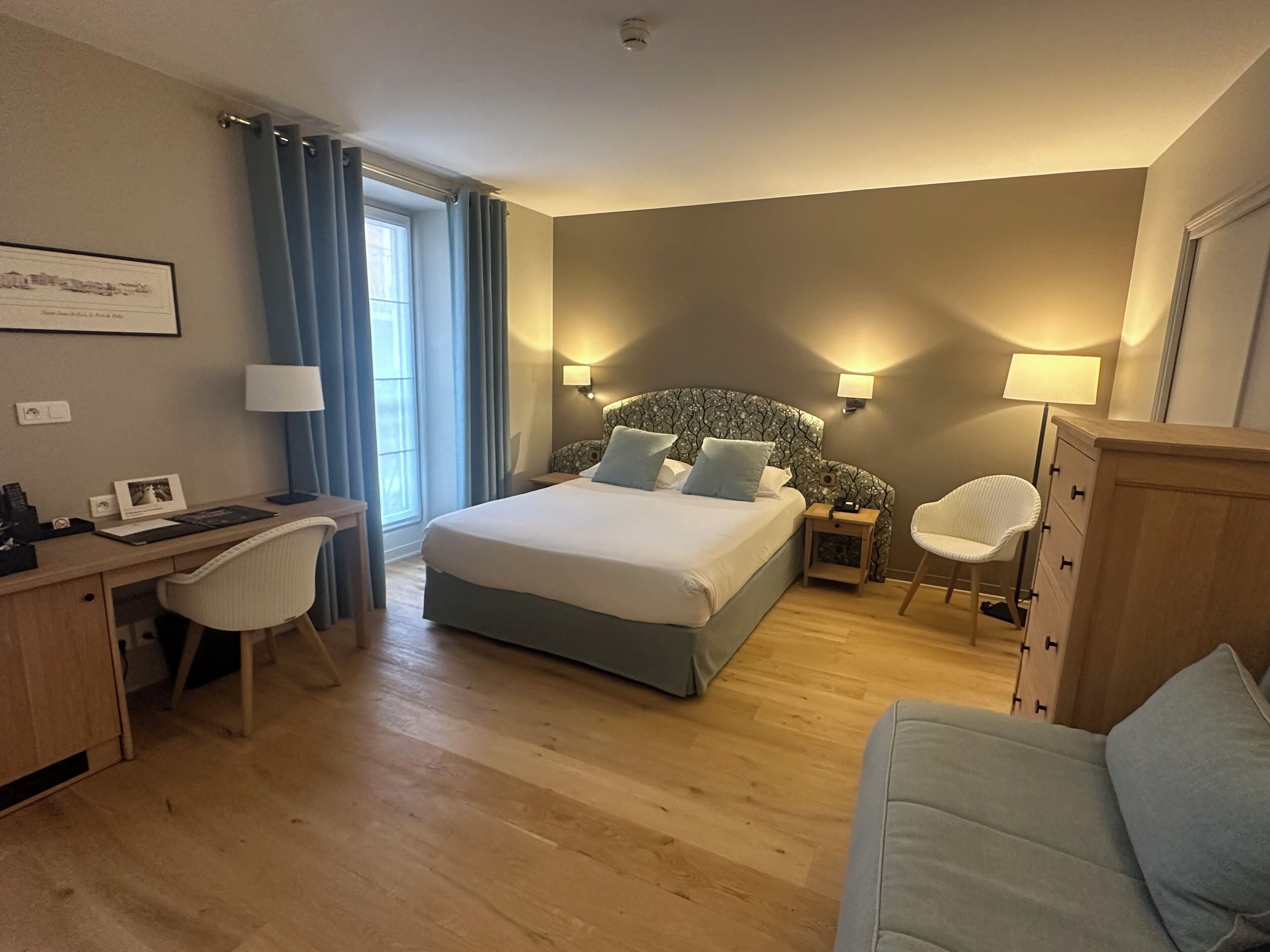 Una habitación de hotel con cama, escritorio, silla y una mesita.