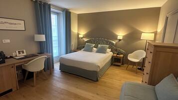 Una habitación de hotel con cama, escritorio, silla y una mesita.