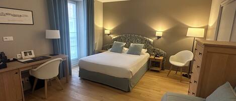 Una habitación de hotel con cama, escritorio, silla y una mesita.