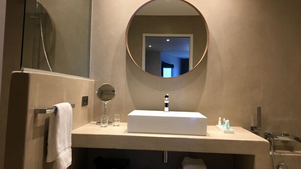 Un baño moderno con un espejo grande, un lavamanos rectangular y un perchero para toallas.