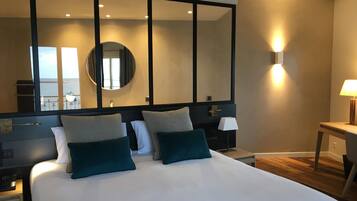 Una habitación de hotel con una cama grande, una mesita de noche, una lámpara y un espejo.
