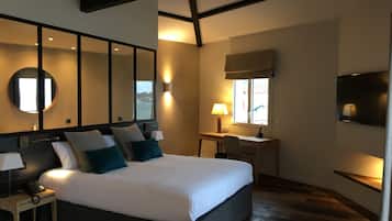 Habitación de hotel moderna con una cama grande, un escritorio, un televisor y un amplio ventanal con vistas.