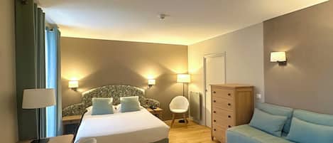 Una habitación de hotel con cama, escritorio, silla, cómoda y sofá.