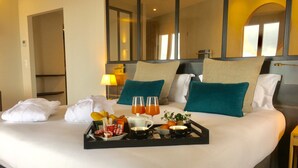 Een keurig opgemaakt bed met een dienblad met ontbijtartikelen, waaronder toast, fruit en sap, in een hotelkamer.