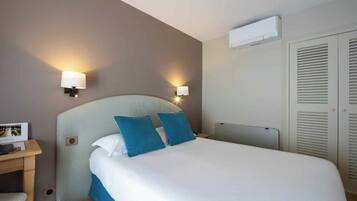 Een hotelkamer met een bed, bedlampjes, een bureau met een fotolijstje en een kledingkast.