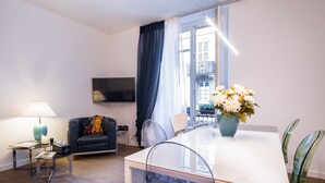 A modern living room with a sofa, a glass table, and a TV mounted on the wall. - Como Design Apartment (Como)