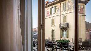 A view from a balcony with a wrought iron railing, a building with green shutters, and a balcony with potted plants. - Como Design Apartment (Como)