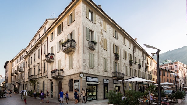 A historic building with multiple floors, balconies with plants, and storefronts. - Como Design Apartment (Como)