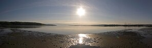 En stilla sjö med en klar himmel, en avlägsen strand och en brygga med båtar.