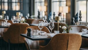 A restaurant interior with tables set for dining, featuring brown leather chairs and clear glassware. - Hotel Wassersleben (Harrislee)