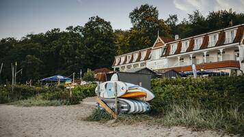 A beach with surfboards and a building with a red roof.