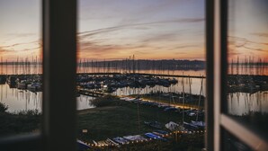 A marina with boats docked, a grassy area, and a distant bridge. - Hotel Wassersleben (Harrislee)