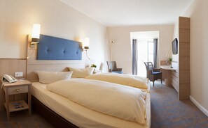 Ett hotellrum med en stor säng, sängbord, ett skrivbord och en stol.