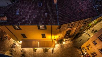 A courtyard with a tiled roof, a wooden bench, and a building with multiple windows.