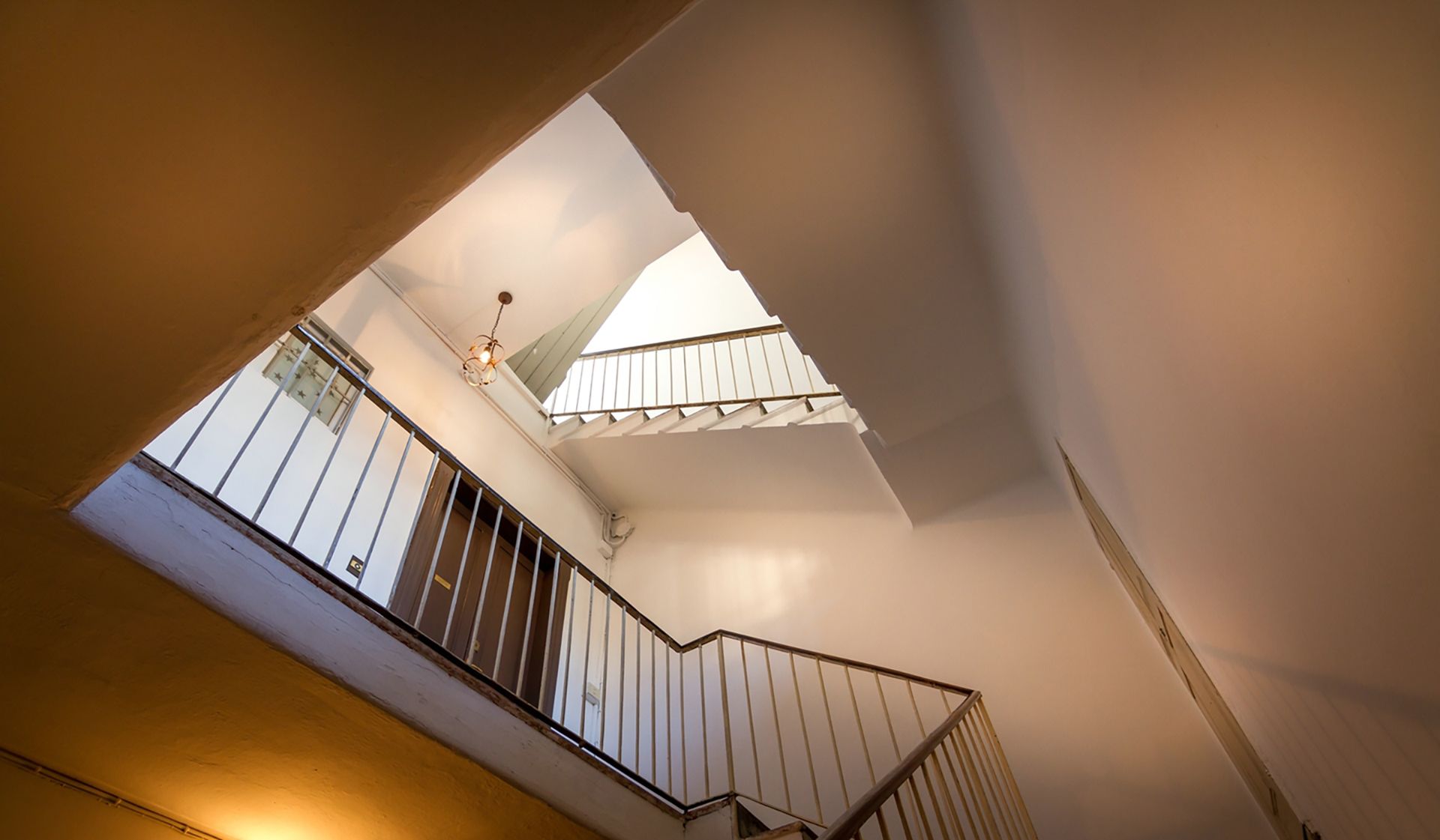 Un escalier offrant une vue sur le ciel et un luminaire suspendu.
