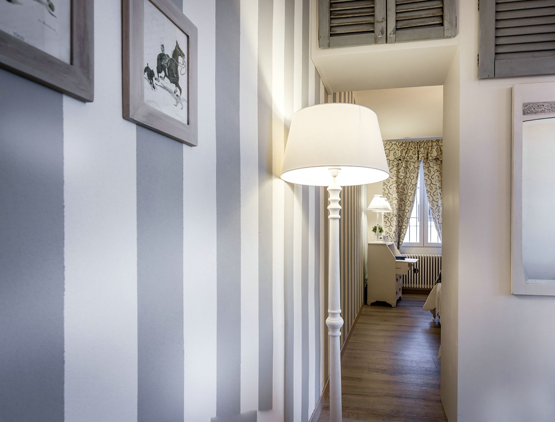 A hallway with a lamp, a radiator, and a window with curtains.