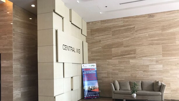 Een receptie met een 'CENTRAL W3' bord, een promotieposter, een bank en een bijzettafeltje.