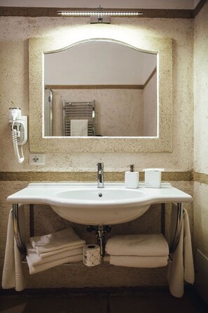 A bathroom with a large mirror, a sink, towels, and a hairdryer.