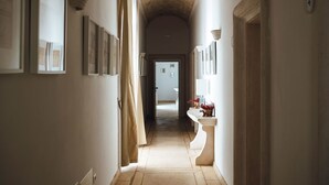 A corridor with framed architectural drawings on the walls, a curved ceiling, and a doorway leading to another room.