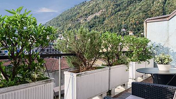 A terrace with a view of a hillside, outdoor furniture, and a white railing. - Domus (Como)