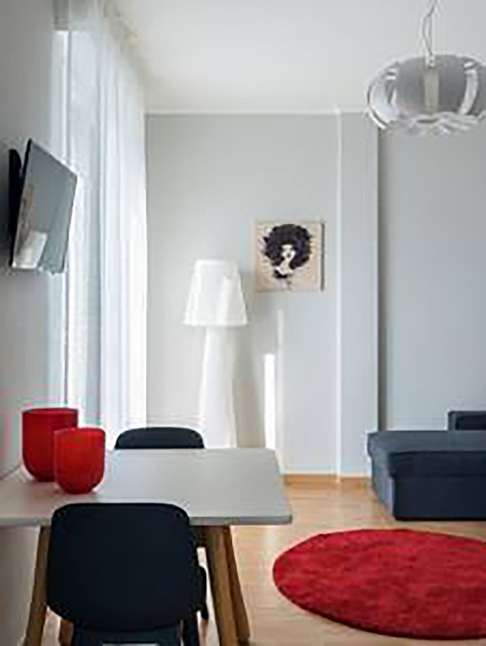 Un salon moderne avec un coin repas, un tapis rouge et une lampe blanche.