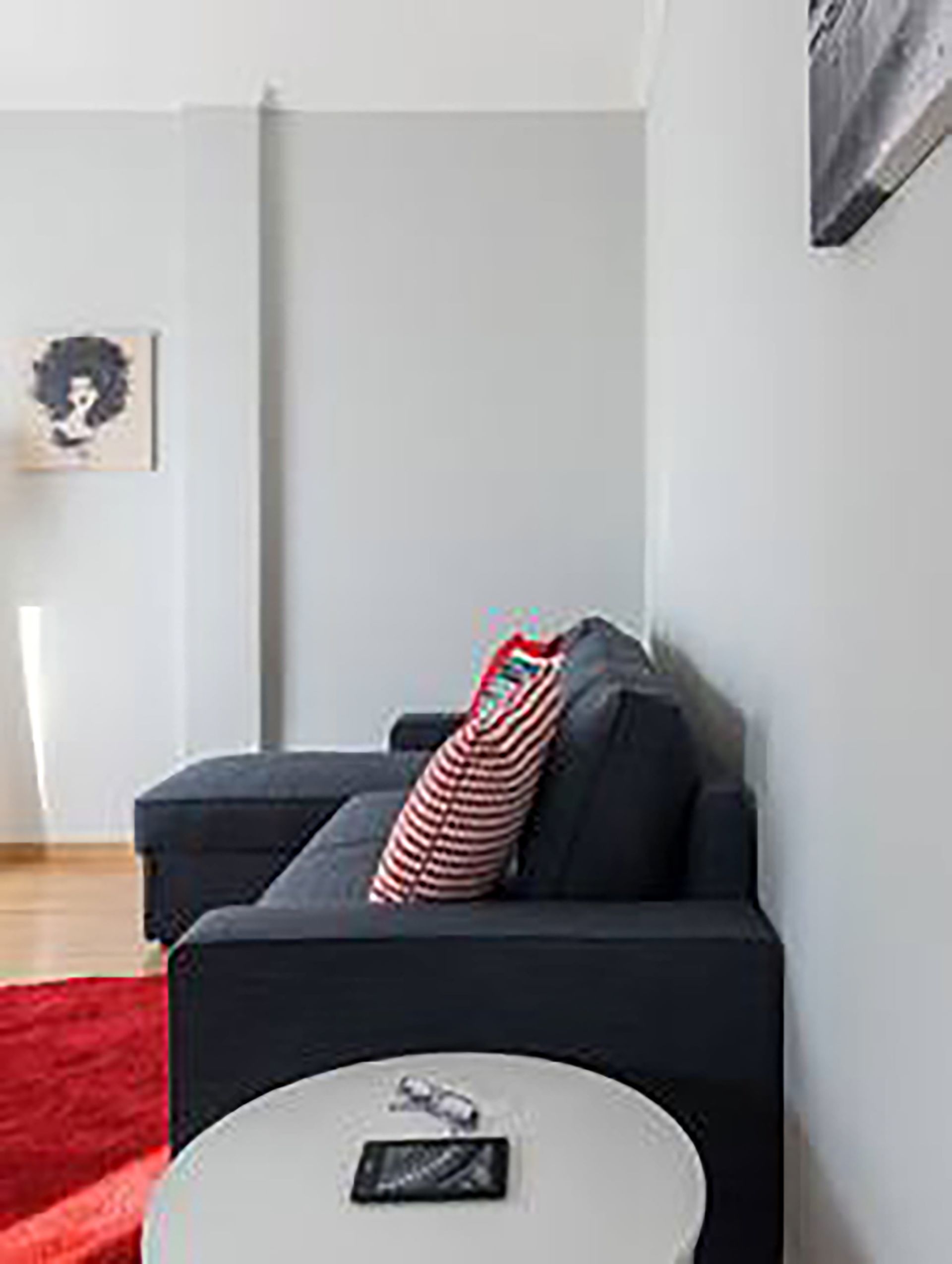 A modern living room with a dark sofa, a red rug, and a white coffee table.