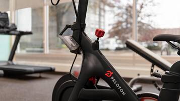 Una bicicleta estática con manillar rojo y el nombre de la marca 'PELOTON' en el cuadro.