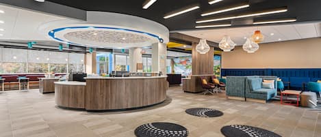 A modern lobby with a reception desk, seating areas, and a large window offering a view.