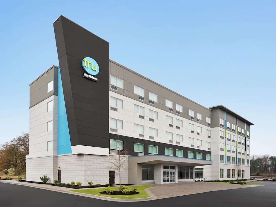 Un hôtel moderne, avec un logo bien visible, plusieurs étages et une entrée abritée.