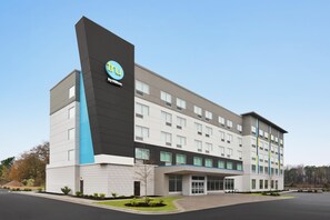 Un moderno edificio de hotel con un logotipo destacado, varios pisos y una entrada cubierta.