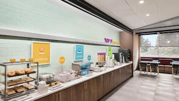 A breakfast bar with various food items and a seating area with tables and chairs.