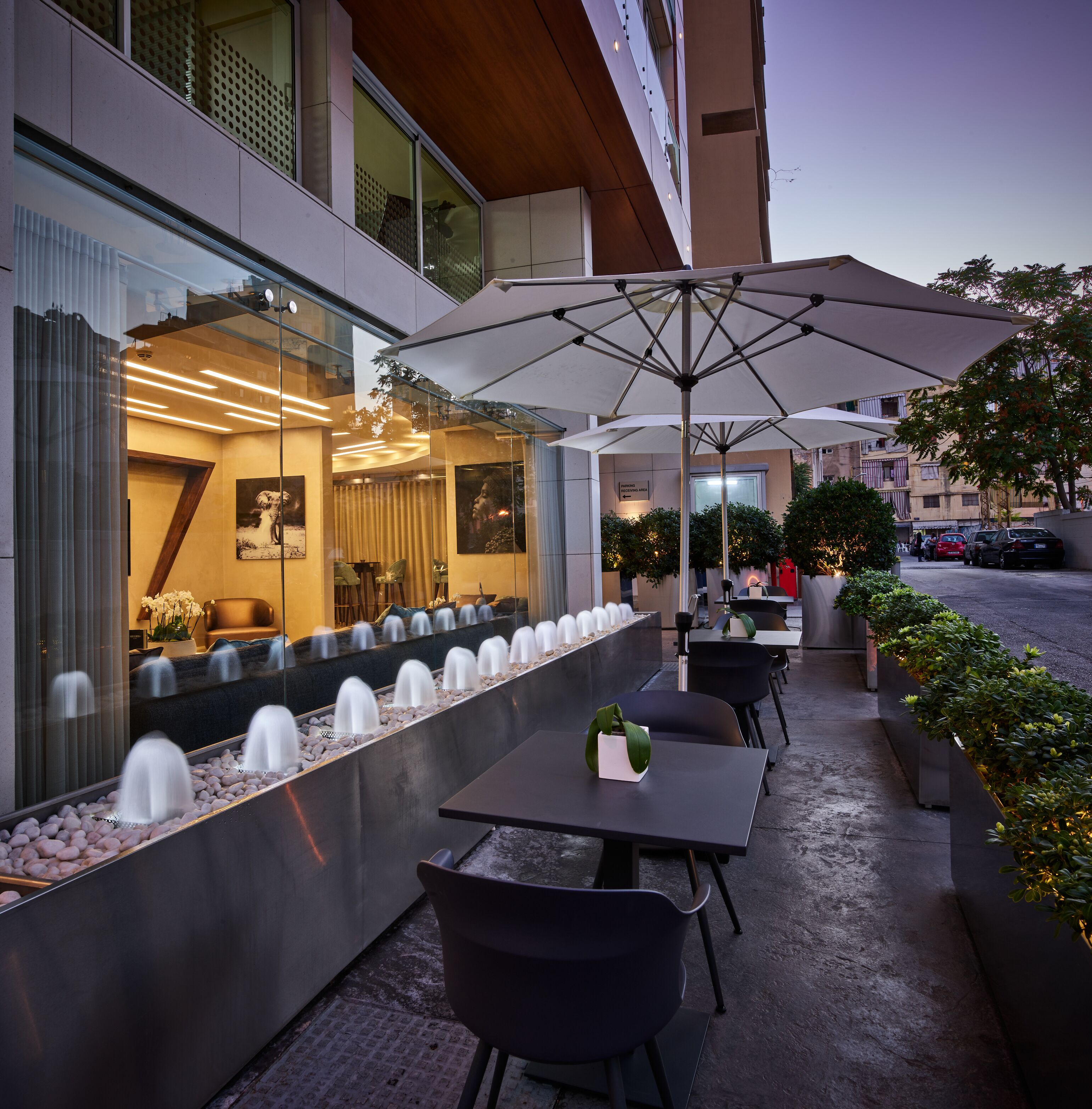 An outdoor seating area with tables and chairs, a water feature, and a large umbrella.