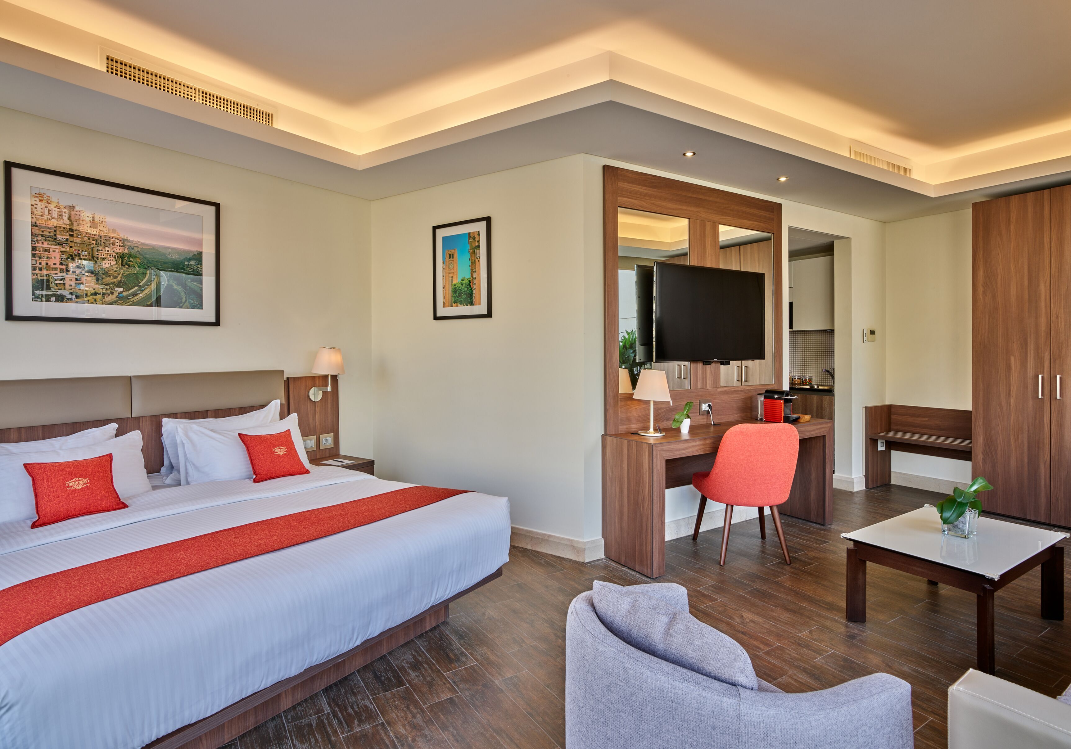 Quarto de hotel com uma cama grande, uma escrivaninha, uma televisão e um espaço de estar.