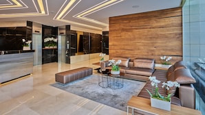 A modern lobby with a reception desk, leather seating, and a wooden accent wall. - Sodeco Suites (Beirut)