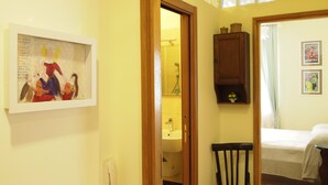 A room with a bed, a wooden chair, a small cabinet, and a painting on the wall. - Casa Laurino B&B (Naples)