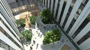 Un edificio moderno con un patio central que cuenta con zonas de estar y vegetación.