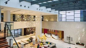 A spacious lobby with a high ceiling, a reception desk, a staircase, and a seating area with cushions and birdcages. - Millennium AL Barsha (Dubai)