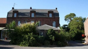 A two-story brick house with a sloped roof, multiple windows, and a garage. - La Chaiserie (Romeries)