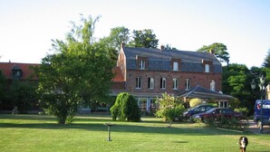 A large brick building with a sloped roof, surrounded by a well-maintained lawn and trees. - La Chaiserie (Romeries)