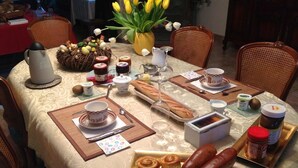 A dining table set with breakfast items including bread, pastries, and condiments. - La Chaiserie (Romeries)