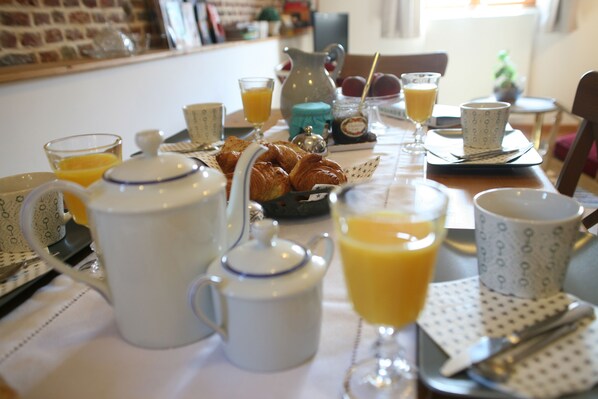 Una mesa de desayuno con croissants, zumo de naranja y una jarra de café.