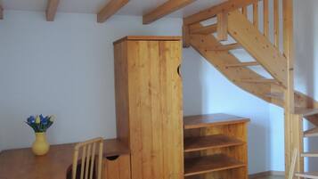 A room with a wooden desk, a chair, a cabinet, and a wooden staircase.