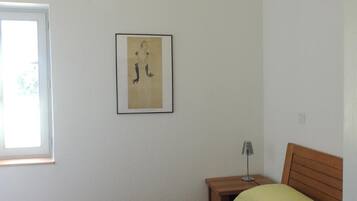 A bedroom with a bed, a bedside table, a lamp, and a window.