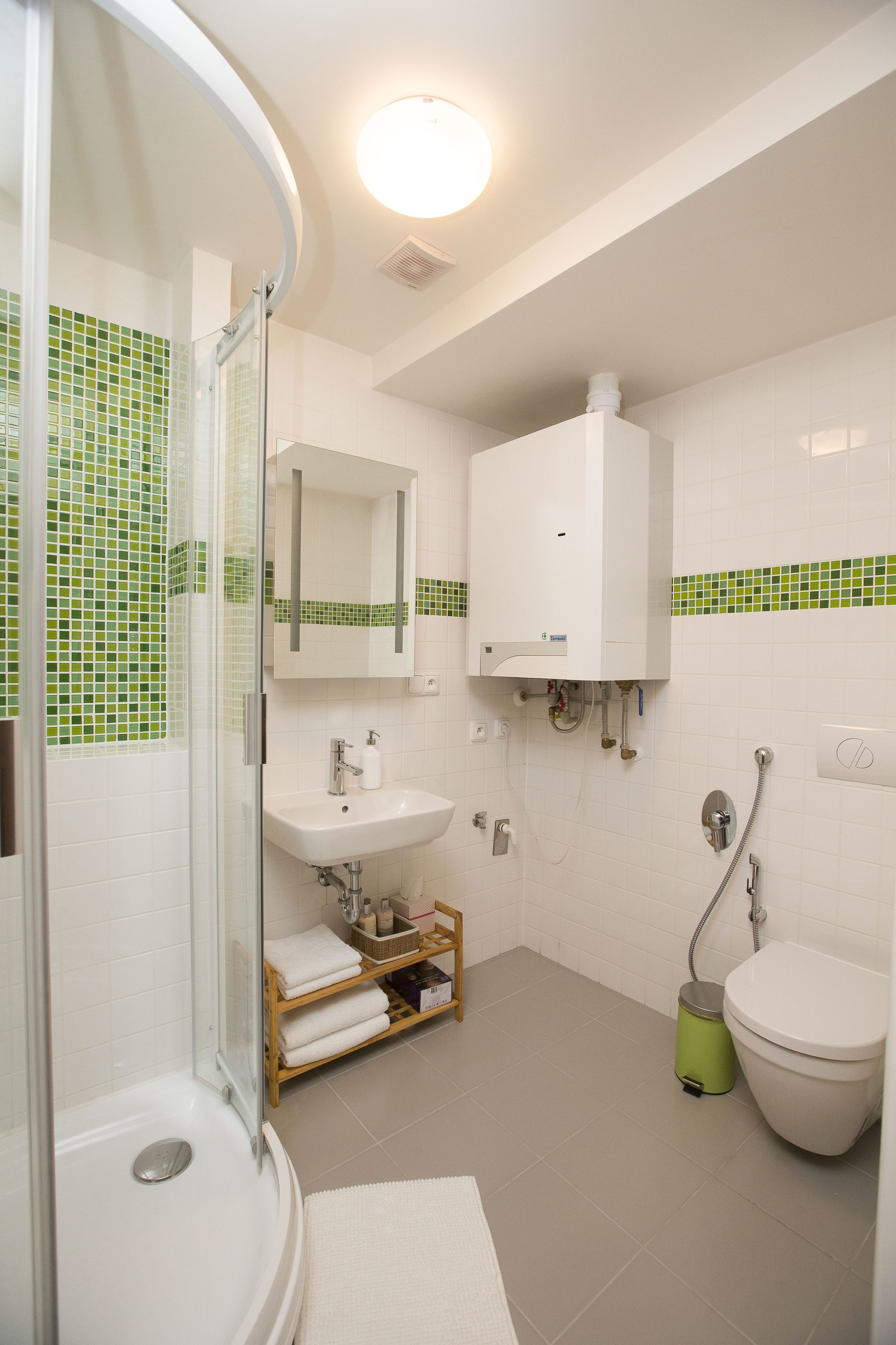 A bathroom with a glass shower enclosure, a sink, a toilet, and a mirror.