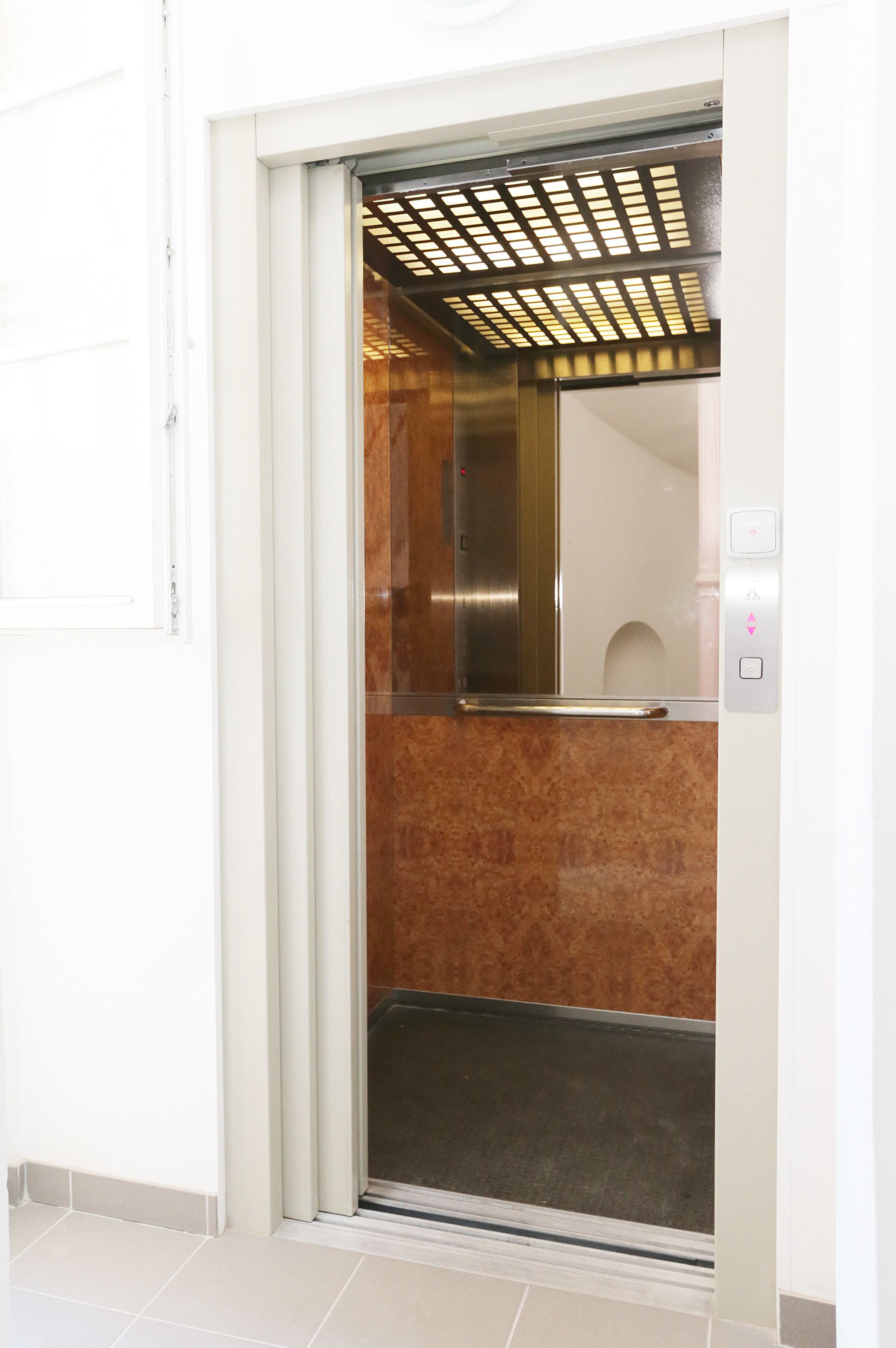 Een lift met een metalen interieur en een bedieningspaneel met knoppen voor de richting.