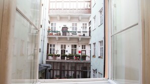 A narrow corridor with a window at the end, leading to a multi-story building with balconies and windows. - Greg Apartments Kampa Prague (Prague)