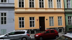 A multi-story building with a yellow facade, multiple windows, and a door. - Greg Apartments Kampa Prague (Prague)