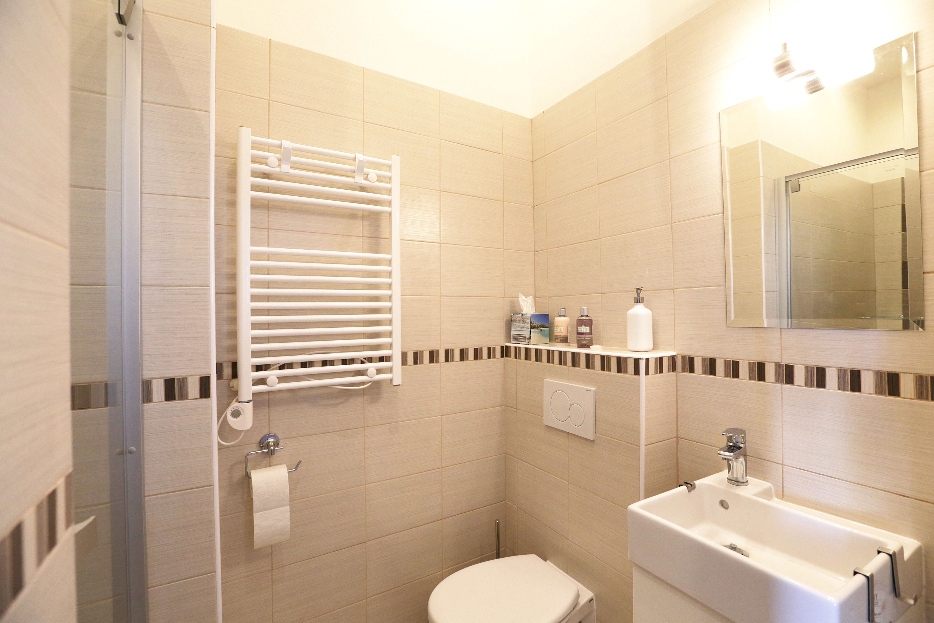 A bathroom with a toilet, sink, towel rack, and shower.
