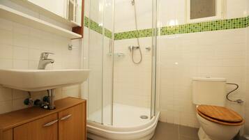Une salle de bain avec une douche à parois de verre, un meuble-lavabo en bois et des toilettes avec un abattant en bois.