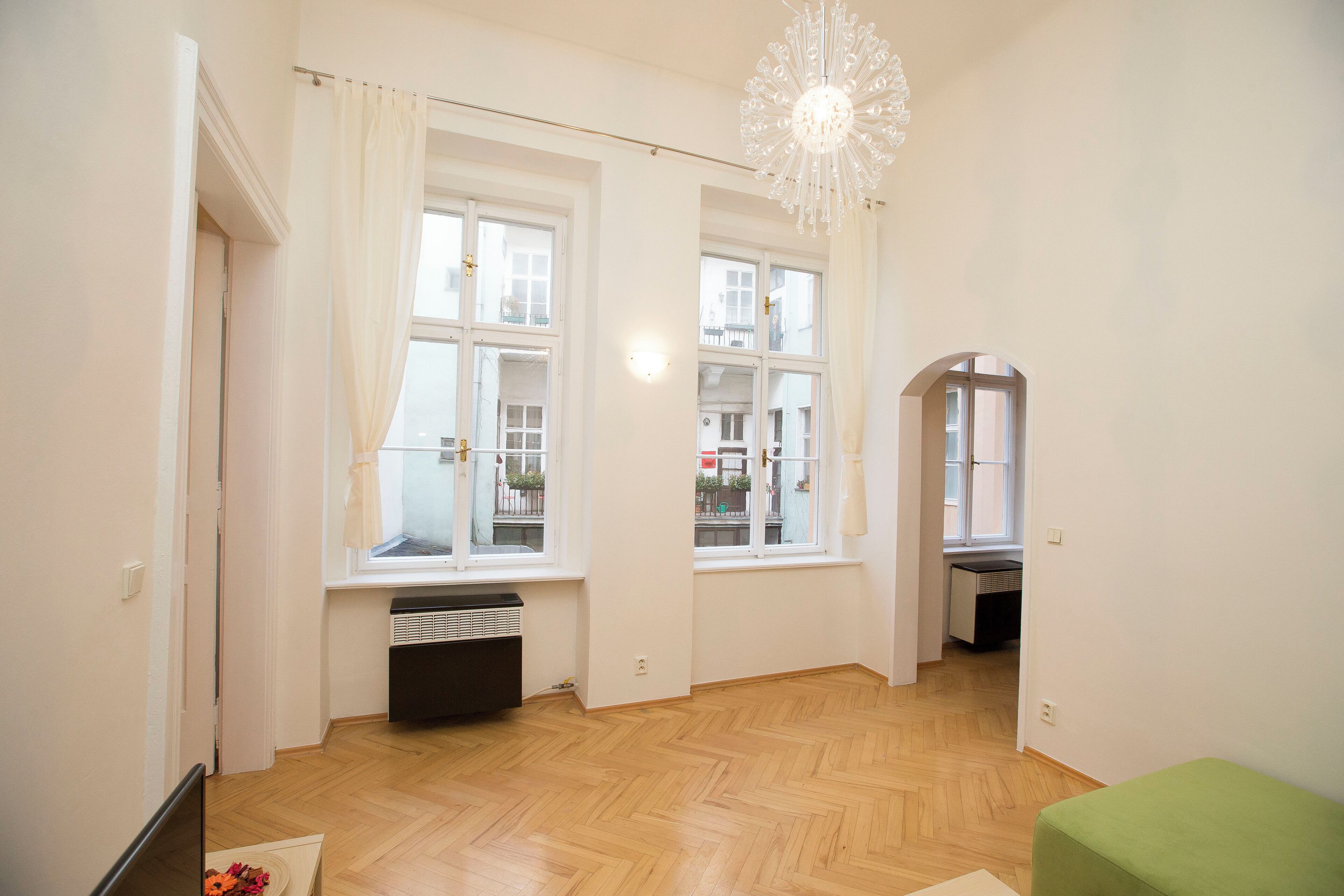 A spacious room with large windows, a wooden floor, and a green bench.